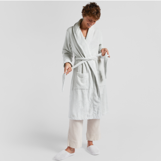 A woman wearing a Classic Turkish Cotton Robe and white slippers.