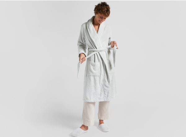 A woman wearing a Classic Turkish Cotton Robe and white slippers.