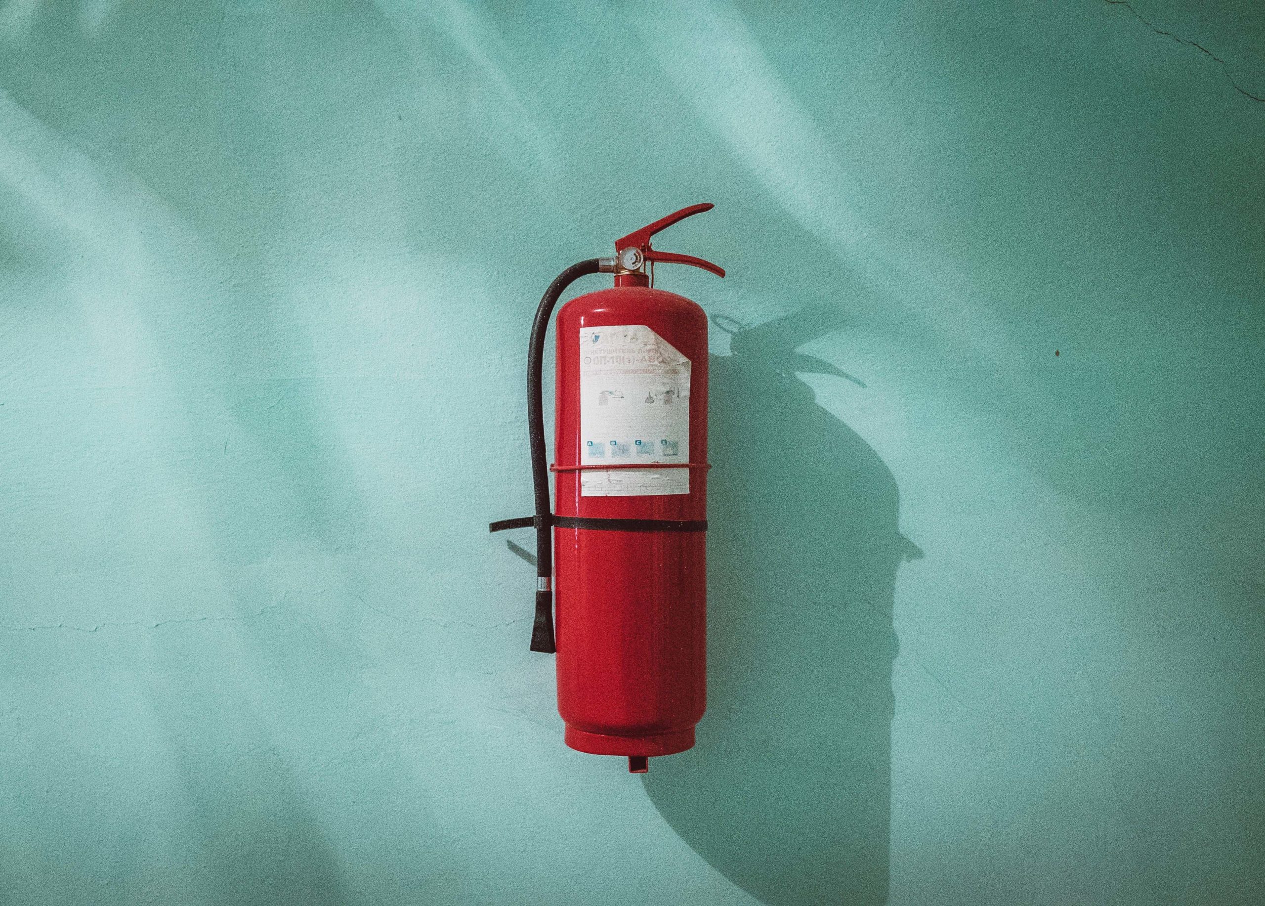 fire extinguisher hanging on teal wall