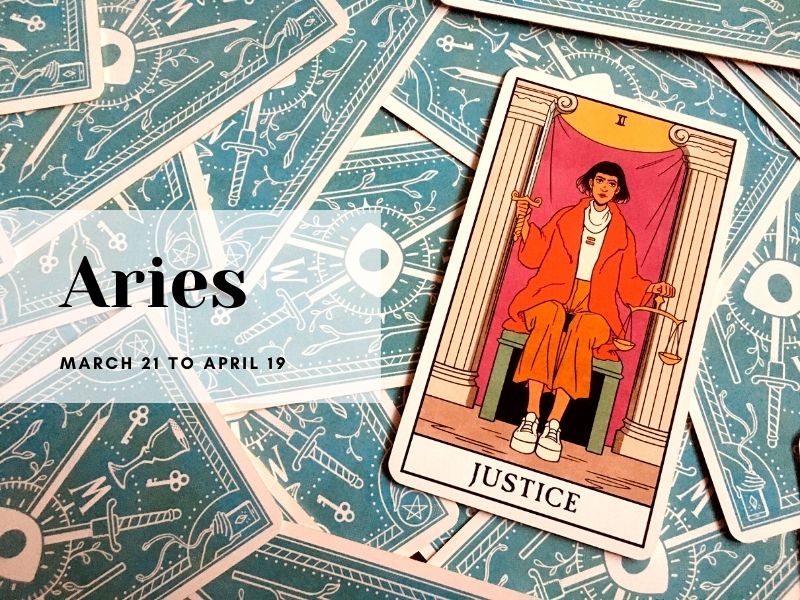 Red and orange tarot card with a dark haired woman sitting on a chair with the word Justice beneath her