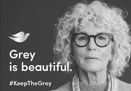 Dove brand's Instagram post in greyscale of a woman with curly grey hair and glasses. It reads: Grey is beautiful #KeepTheGrey