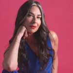 Stacy London, in a blue dress, posing on a pink background after The State of Menopause.