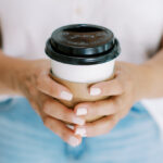 Women's hands holding to-go coffee cup