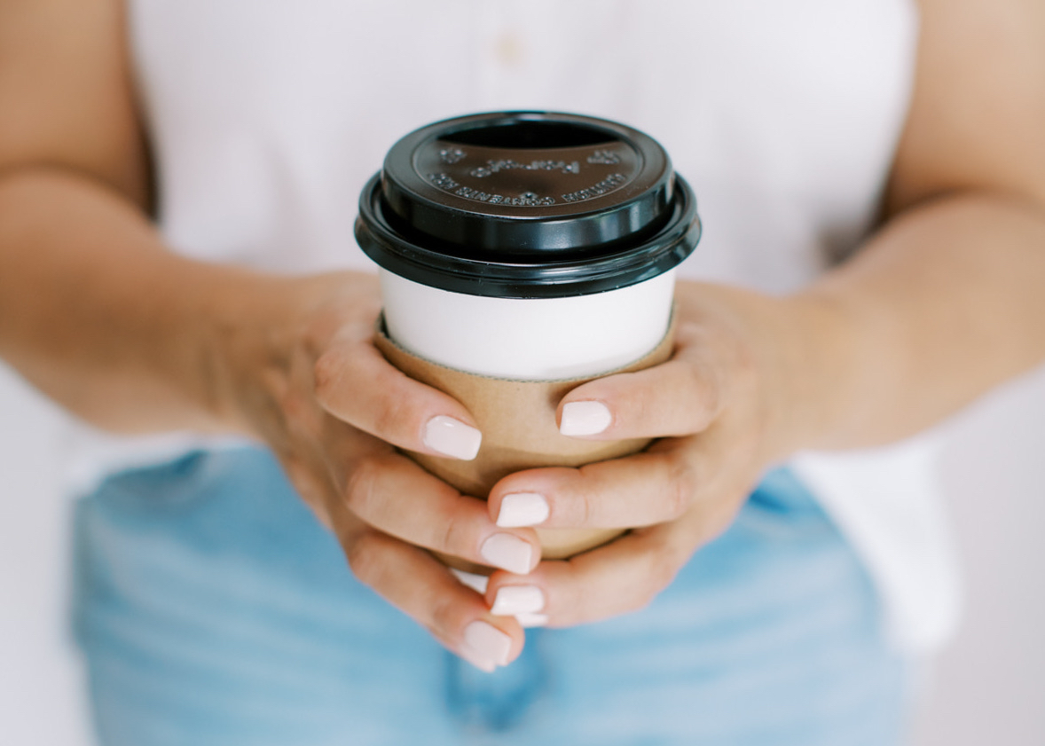 Women's hands holding to-go coffee cup