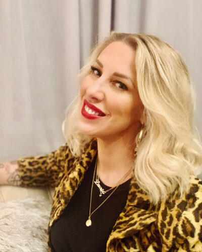 Lauria Locsmondy, a woman in a leopard print jacket, sitting on a couch.