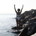 Woman raising arms to skin on beach