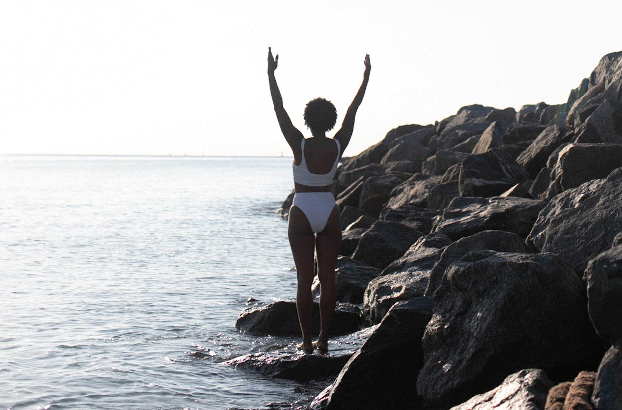Woman raising arms to skin on beach