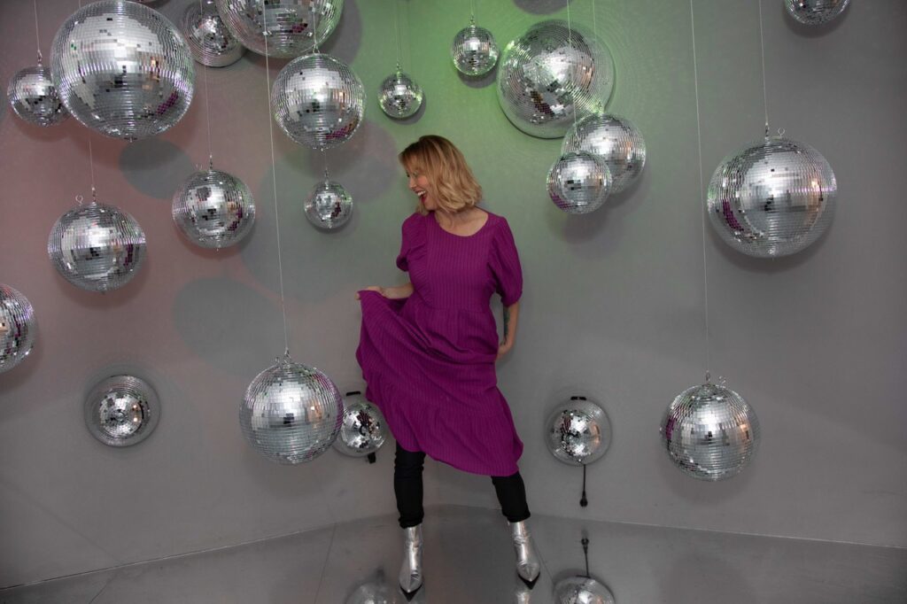 Joanne Fiddy dancing with glittering balls in the background