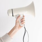 woman's hand holding white blow horn