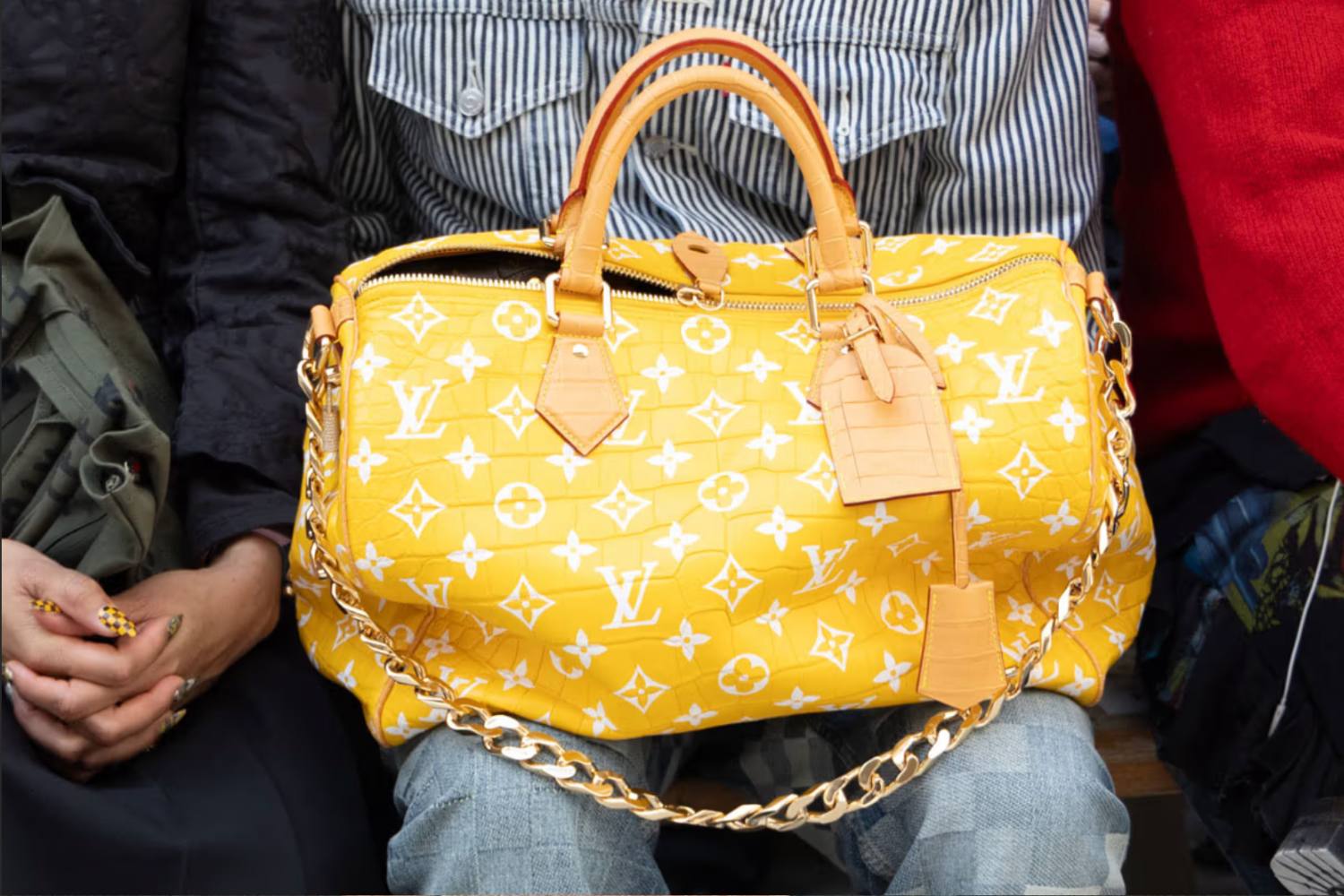 Yellow Louis Vuitton handbag with gold chain, on a lap