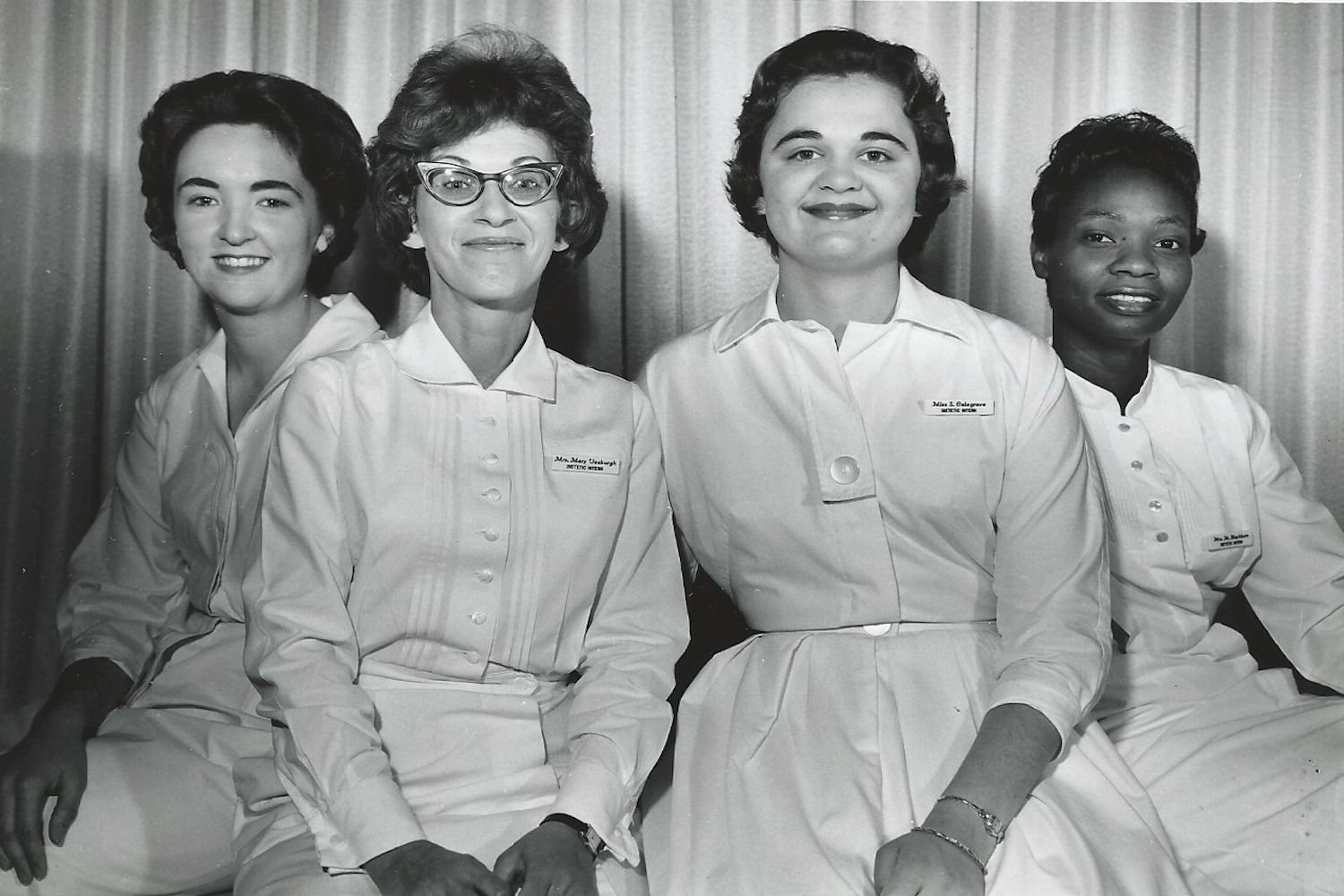 Vintage photo of four women in white uniform dresses