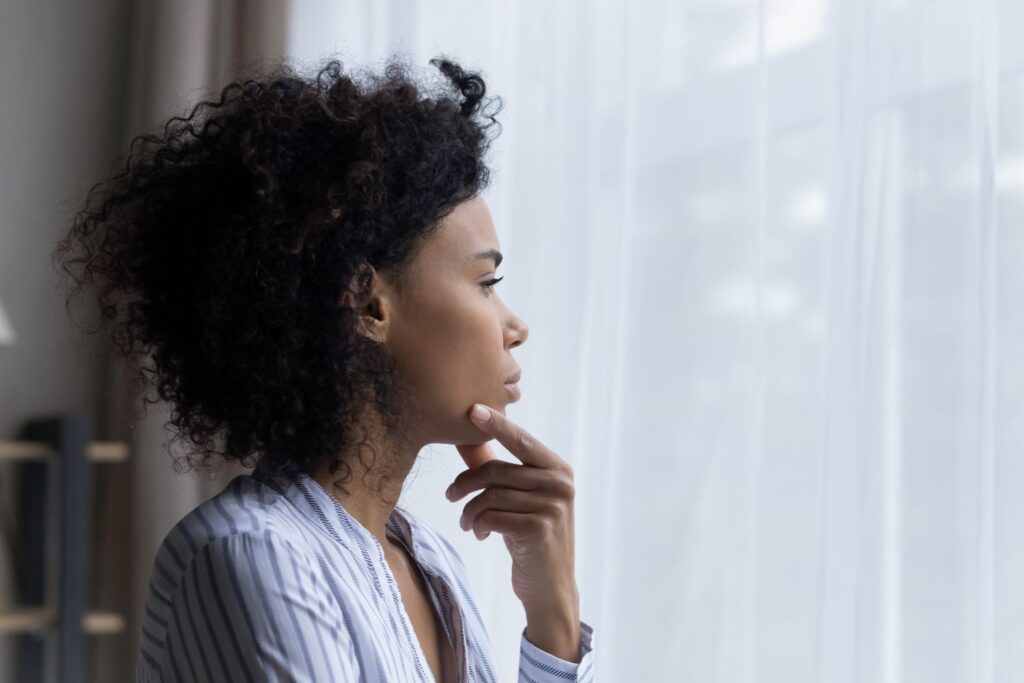 Photo of Black woman looking out a window