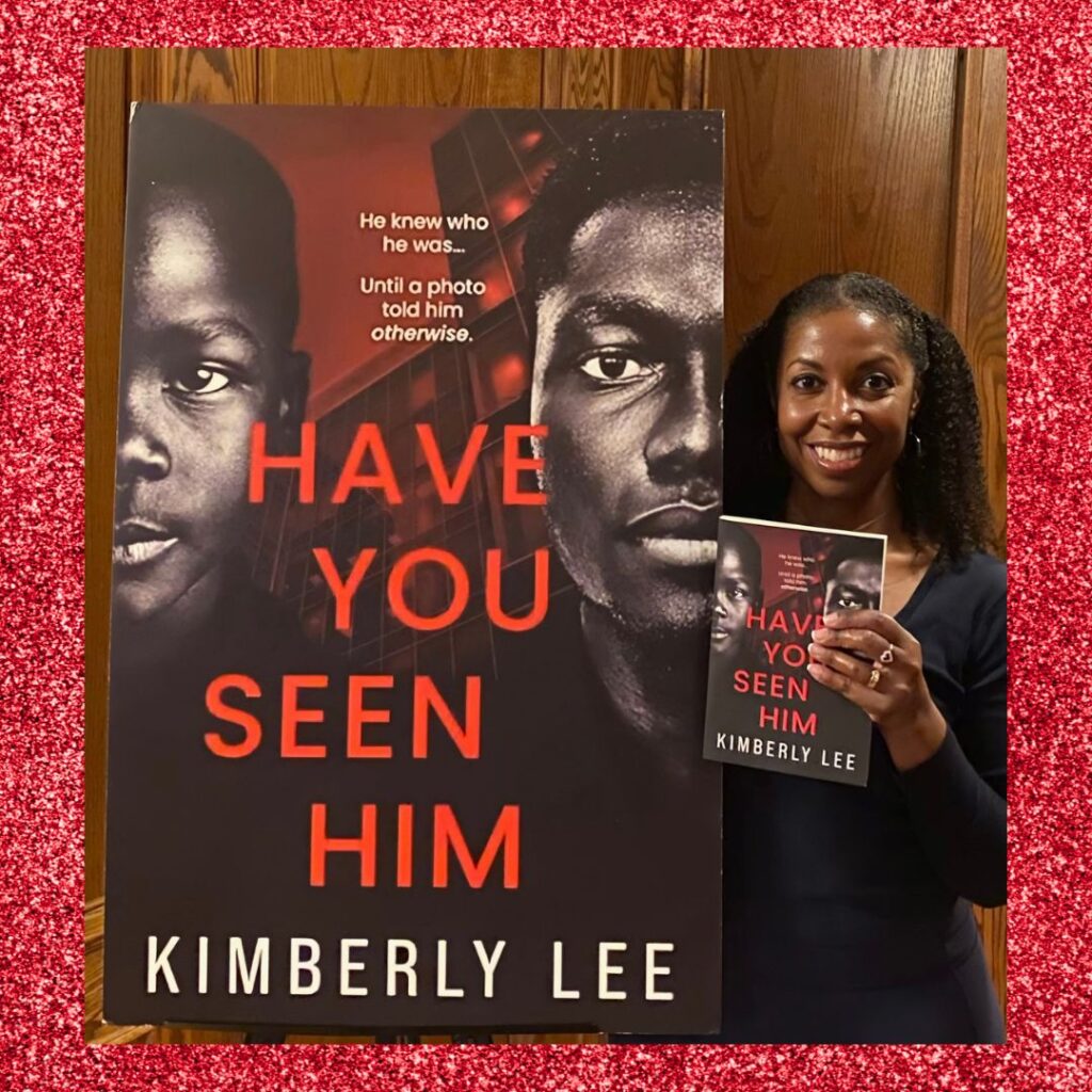 A photo of author Kimberly Lee standing next to a large poster of her book, Have You Seen Him