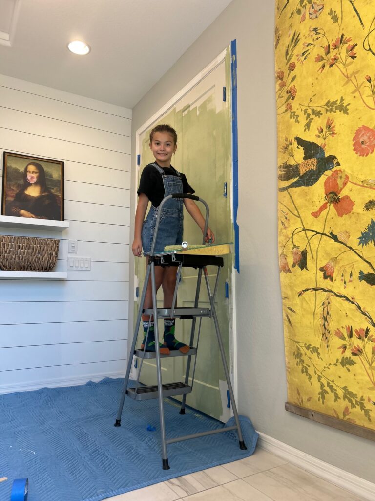 10-year-old girl painting a door Sherwin Williams Bahia green.